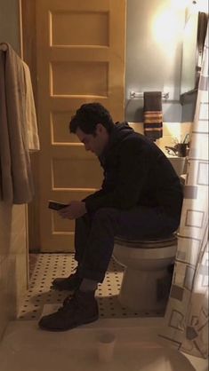 a man sitting on top of a toilet in a bathroom