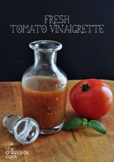 a bottle of tomato sauce sitting on top of a wooden table next to a pepper shaker