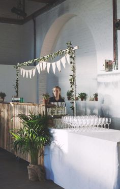 a woman standing behind a counter filled with wine glasses