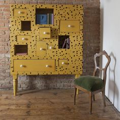 a chair sitting in front of a yellow cabinet