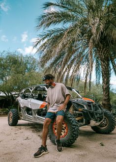 a man sitting on top of a four - wheeler parked next to a palm tree