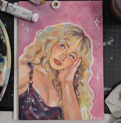 a painting of a blonde woman with her hand on her face next to some paintbrushes