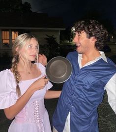 a man and woman dressed up in costumes standing next to each other outside at night