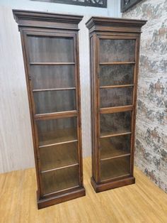 two wooden bookcases sitting on top of a hard wood floor next to each other