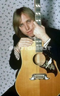 a man holding an acoustic guitar in front of his face and posing for the camera