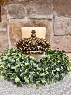 a candle sits on top of a table covered in greenery and beads, next to a decorative crown