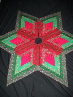 a red and green quilted star on a black surface