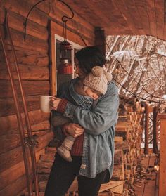 a woman holding a child in her arms while standing on the porch of a cabin