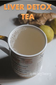 a white plate topped with a cup of tea next to some lemons and ginger