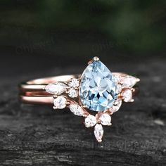 a ring with an aqua blue topazte surrounded by white and pink diamonds on a piece of wood