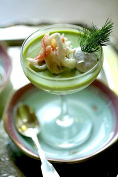 a green drink with shrimp and celery garnish in it on a plate