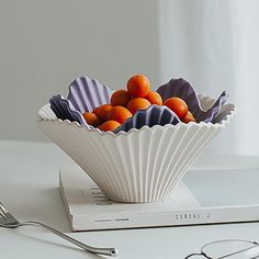 a white bowl filled with oranges on top of a table