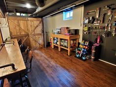 the inside of a garage with wood floors and various tools hanging on the wall above it