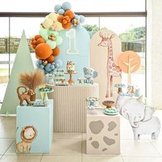 an assortment of baby shower items on display in front of a window with trees and balloons