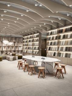 the interior of a store with tables and stools in front of bookshelves