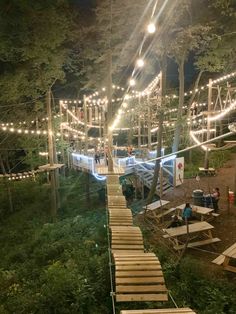 an outdoor area with wooden steps and lights strung from the trees, surrounded by greenery