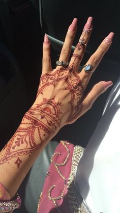 a woman's hand with henna tattoos on her left arm and the middle finger