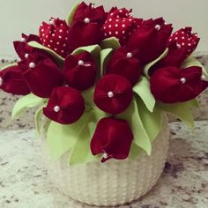 a white vase filled with red flowers on top of a counter