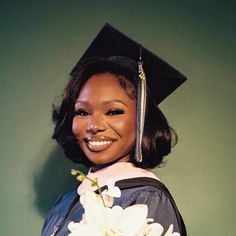 a woman wearing a graduation cap and gown holding a bouquet of flowers in front of her face