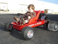 a young boy is sitting in a red toy car