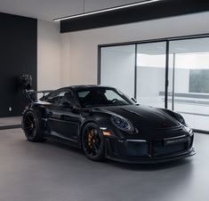 a black sports car parked in front of a large glass windowed room with sliding doors