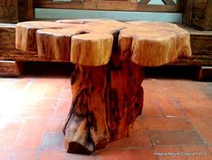 a wooden bench made out of logs sitting on top of a tile floor next to a window