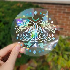 a hand holding up a sticker with a butterfly on it's side and stars in the middle