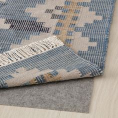 a blue and beige rug on top of a wooden floor next to a gray area rug