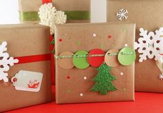 three presents wrapped in brown paper with green and red decorations on them, sitting next to each other