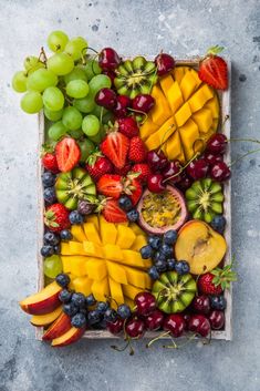 fresh fruits arranged in a square tray on a gray table top view from above stock photo