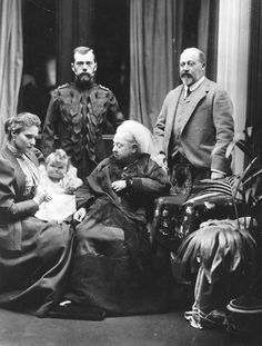 an old black and white photo of several people in formal dress, including a baby