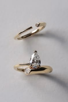 two engagement rings, one with a pear shaped diamond and the other with an arrow