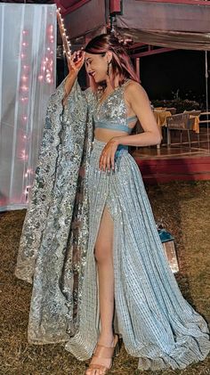 a woman in a blue and silver dress standing under a tent with lights on it