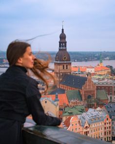 a woman standing on top of a building looking at the cityscape behind her