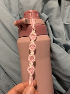 a person holding a pink and white rope wrapped around a water bottle