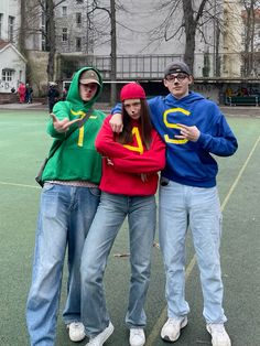 three people standing on a tennis court posing for the camera