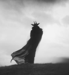 a black and white photo of a woman wearing a crown on top of a hill