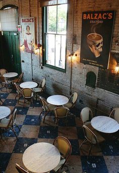 tables and chairs are lined up against the wall in an old building with posters on it