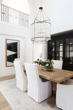 a dining room table with white chairs and a chandelier hanging from the ceiling