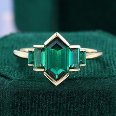 an emerald colored ring is sitting on a green cloth