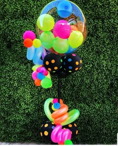 a bunch of balloons that are on top of a pole in front of some grass