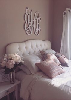 a white bed topped with lots of pillows next to a window filled with curtains and flowers