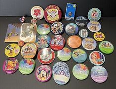 lots of disney pinbacks and badges are on the table next to each other