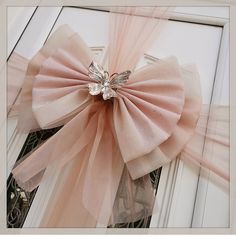 a pink bow on the front door of a house that is decorated with swaroes