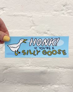 someone holding up a sticker that says honk if you're a silly goose