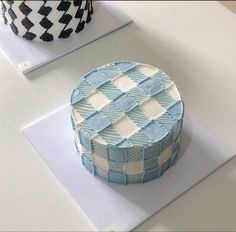 a blue and white cake sitting on top of a table next to a black and white vase