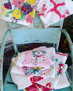 an old blue chair with several napkins stacked on top of each other in front of it