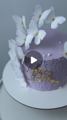 a purple cake with white flowers on top and gold lettering that reads, happy birthday