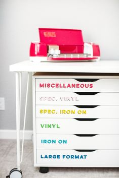 a record player sitting on top of a white table next to a red box with writing on it