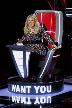 a woman sitting on top of a chair in front of a sign that says i want you